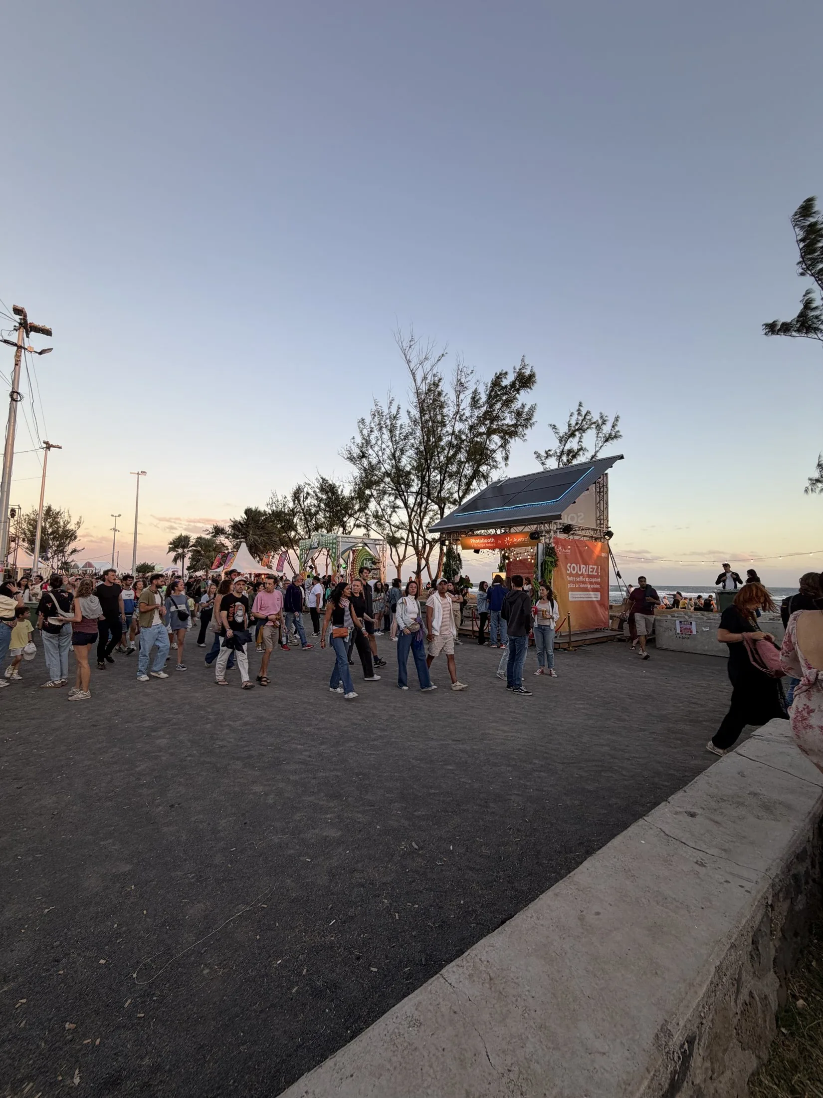 Solar Booth Austral Groupe Énergie (photobooth à l'énergie solaire) au SAKIFO Musik Festival, La Réunion — vue grand angle de l'allée du festival au coucher du soleil
