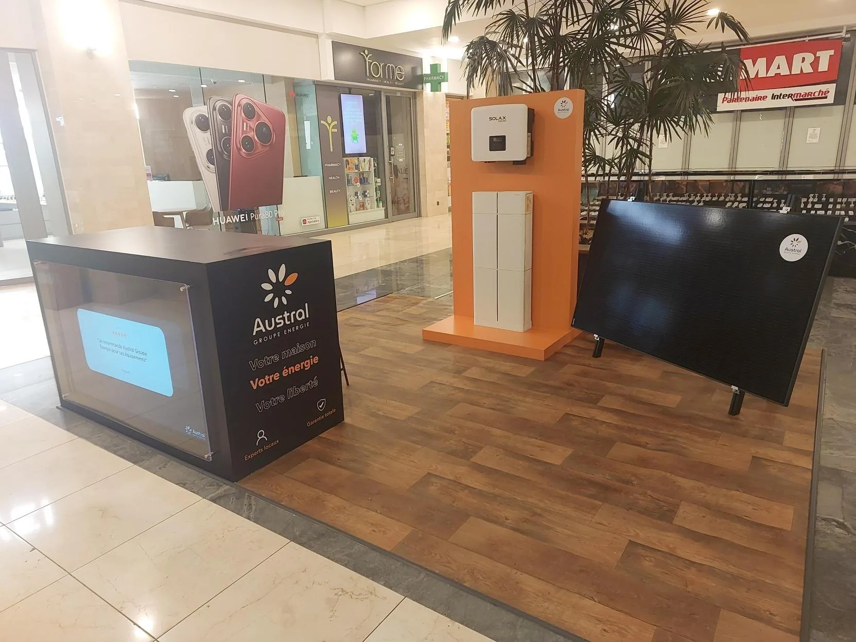 Stand d'exposition Austral Groupe Énergie en galerie commerciale — totem onduleur, batterie et panneau photovoltaïque